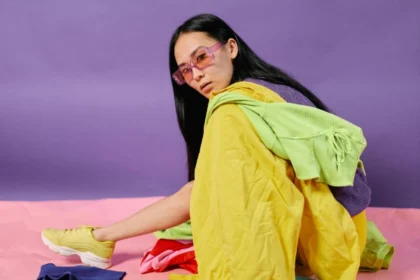 Ragazza seduta circondata da abiti di diversi colori mentre studia gli abbinamenti per un outfit armonioso.