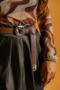 Primo piano di cintura da donna in pelle colore marrone, con fibbia metallica e nodo laterale per Nice to be Woman