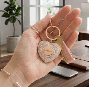 Mano femminile che regge un portachiavi a forma di cuore tempestato di strass con incisione "mamma", idea regalo festa della mamma per Nice to be Woman