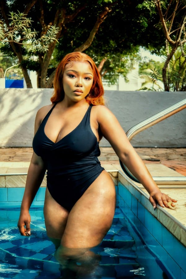 Modella curvy in piscina indossa un costume da bagno donna intero nero con scollo a V e arricciatura