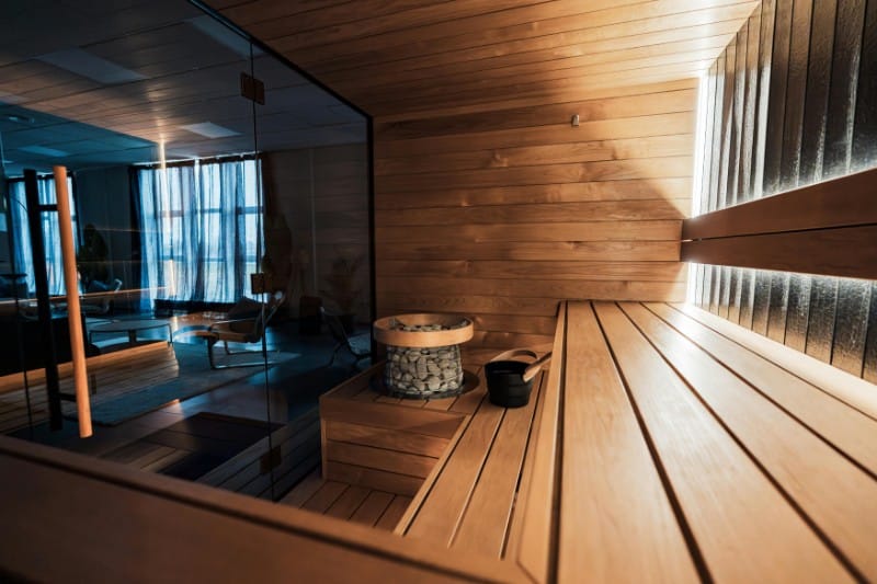Particolare di un ambiente sauna moderno in una Spa con vetrate, pareti e panche in legno e alcuni recipienti