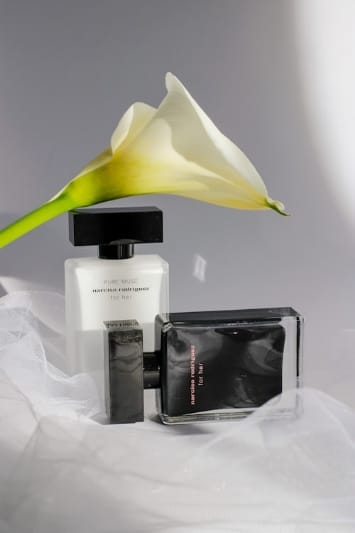 Flaconi Narciso Rodriguez Pure Musc e Narciso Rodriguez for Her eau de parfum, migliori profumi donna primavera estate su un tulle bianco e calla