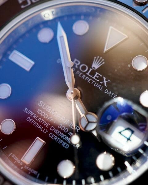 Dettaglio ravvicinato del quadrante di un Rolex Submariner pre-owned, con focus sulla lente Cyclope e le lancette per la verifica dell'autenticità.