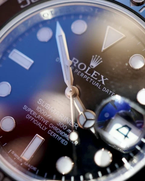 Dettaglio ravvicinato del quadrante di un Rolex Submariner pre-owned, con focus sulla lente Cyclope e le lancette per la verifica dell'autenticità.