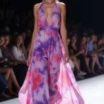 Modella in una sfilata di abiti dal taglio fluido indossa un abito in chiffon a fiori rosa e viola