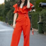 Donna con tuta jumpsuit rossa elegante con rouches sulle spalle e cintura in vita