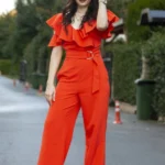 Donna con tuta jumpsuit rossa elegante con rouches sulle spalle e cintura in vita
