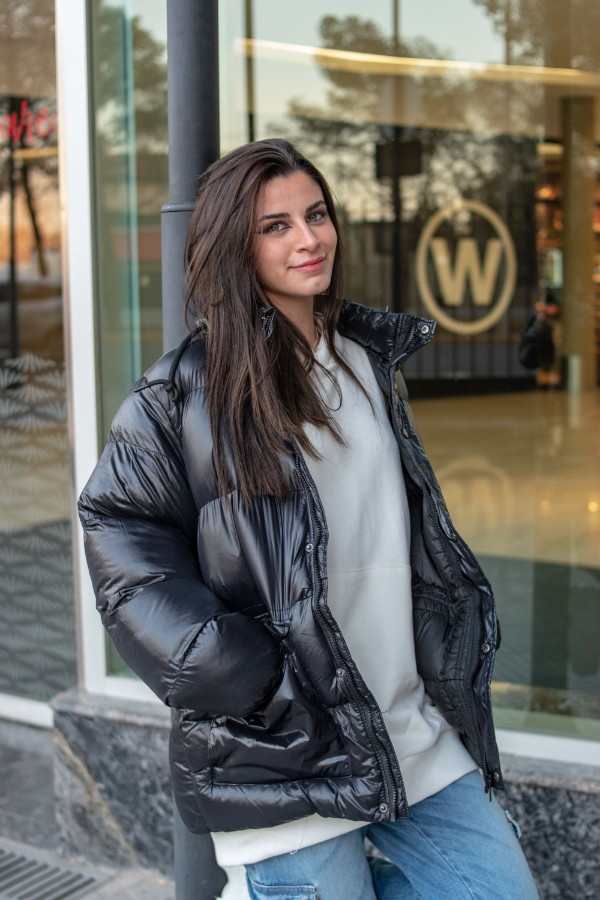 Ragazza indossa un giubbino oversize tra i 5 modelli di giubbini invernali di tendenza in colore grigio scuro, jeans e felpa oversize bianca
