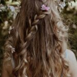 Chioma folta con capelli lunghi e sani intrecciati decorati con fiori rosa per la guida agli integratori per capelli